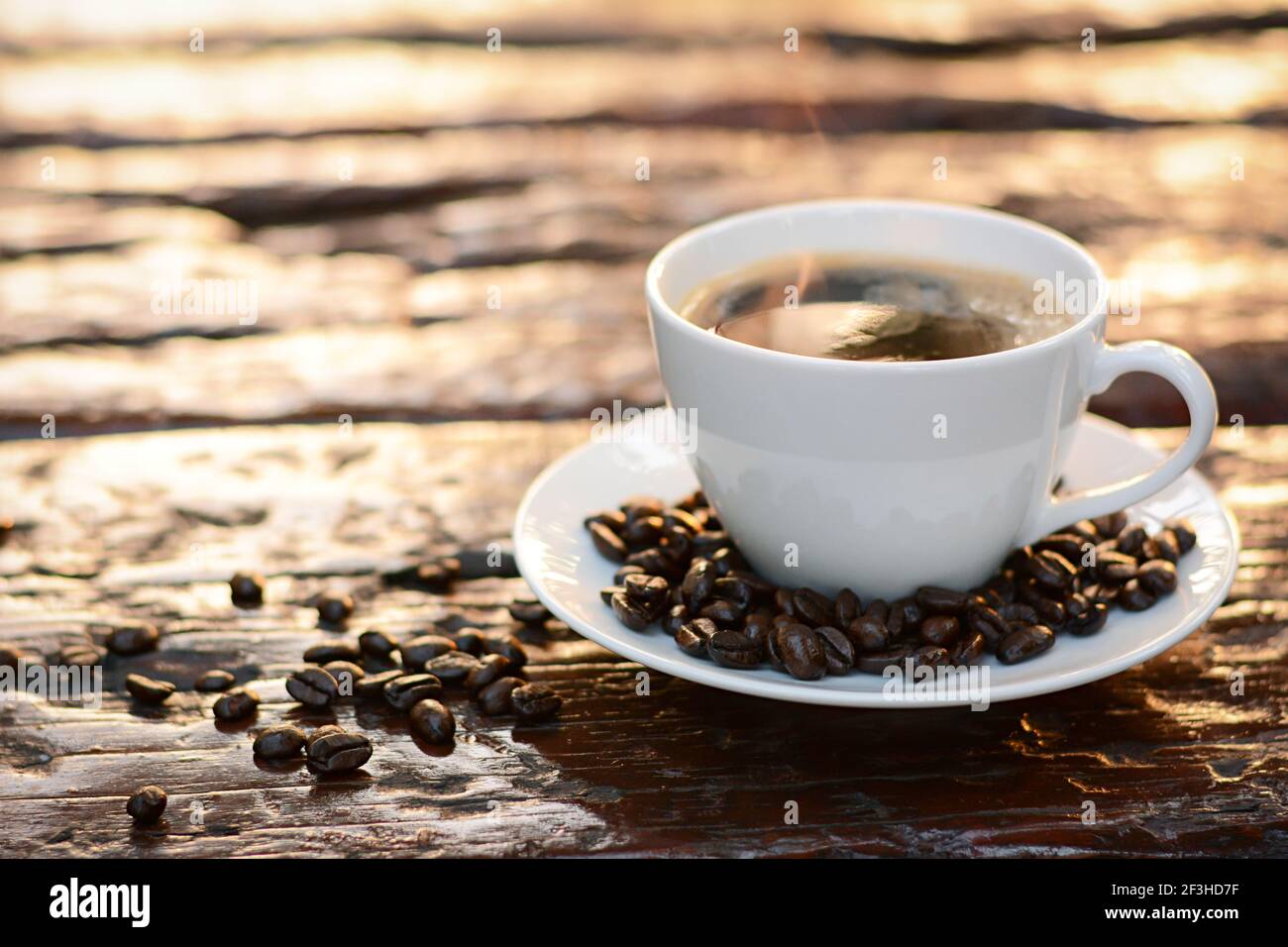 Caffè caldo nella tazza sul vecchio tavolo di legno con chicchi di caffè Foto Stock