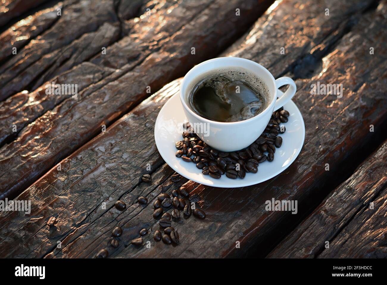 Caffè nero nella tazza sul tavolo di legno vecchio con chicchi di caffè Foto Stock