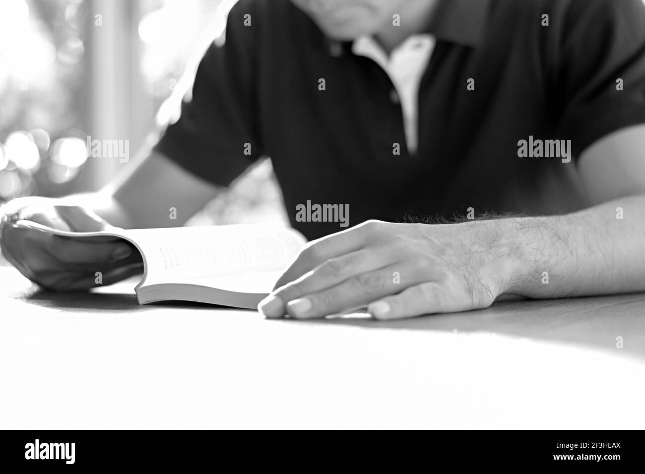 Un uomo che legge libro sul tavolo - effetto monocromatico Foto Stock