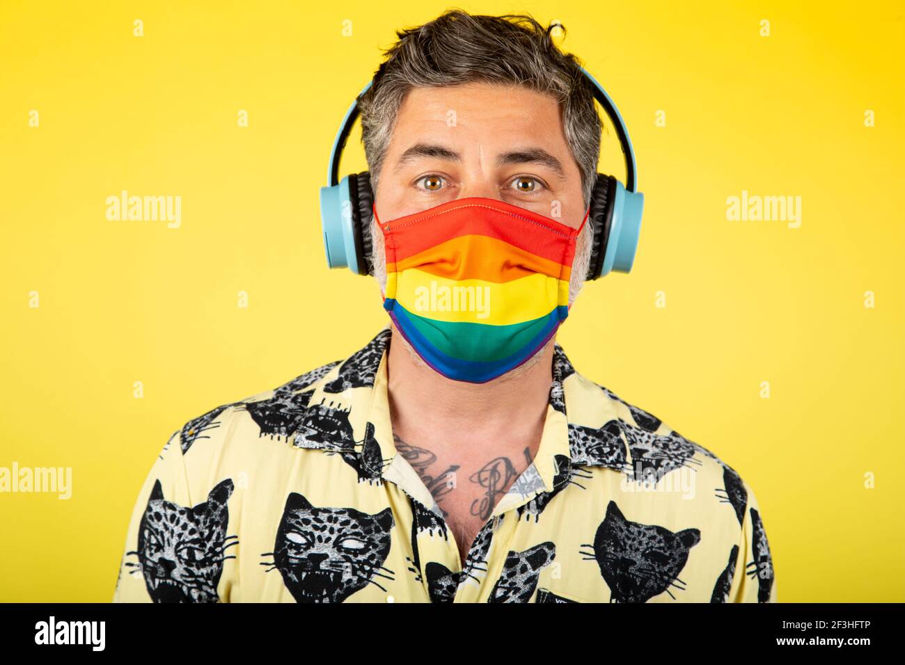 Ritratto di uomo felice con cuffie e maschera gay orgoglio su sfondo giallo  Foto stock - Alamy