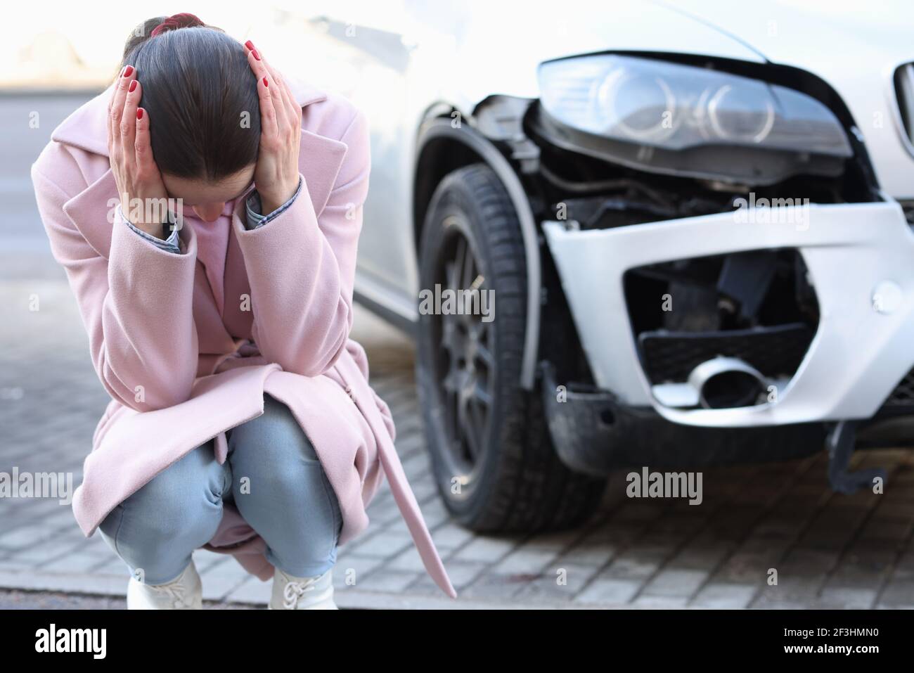 Una donna turbata si siede con la testa giù accanto a. auto sviluppata Foto Stock