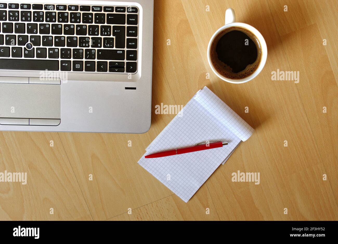 Computer portatile con tazza da caffè, notebook e penna su sfondo in legno, vista dall'alto. Concetto per home Office.Work da casa. Concetto aziendale. Foto Stock