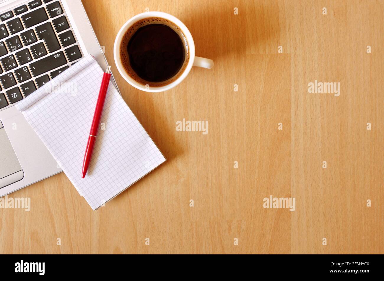 Computer portatile con tazza da caffè, notebook e penna su sfondo di legno, concetto per l'ufficio domestico. Concetto aziendale. Lavoro da casa. Scrivania da ufficio. Foto Stock