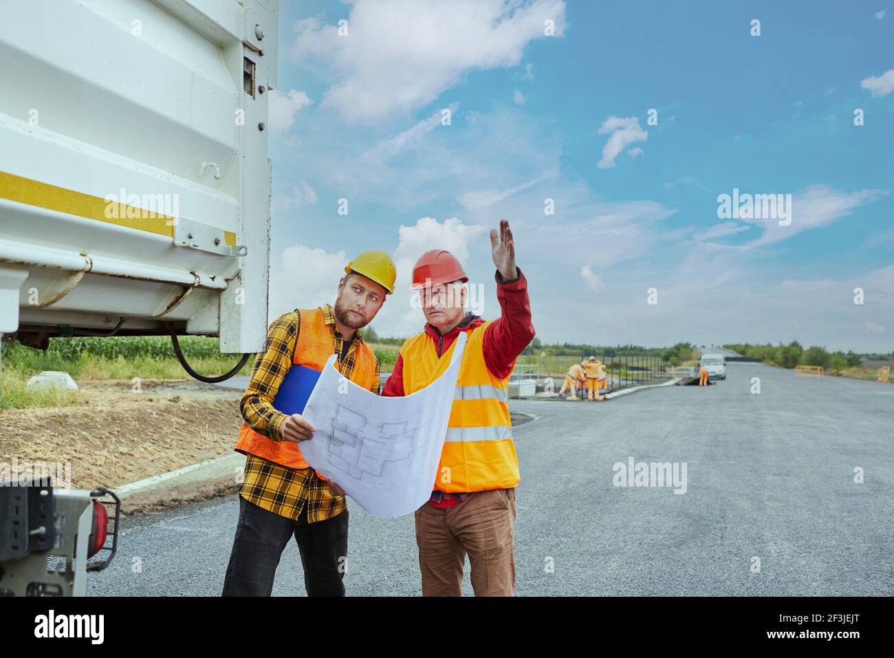 Lavoratore in cantiere per la costruzione di case in nuovo sviluppo area con disegno dell'edificio e pianta del sito Foto Stock