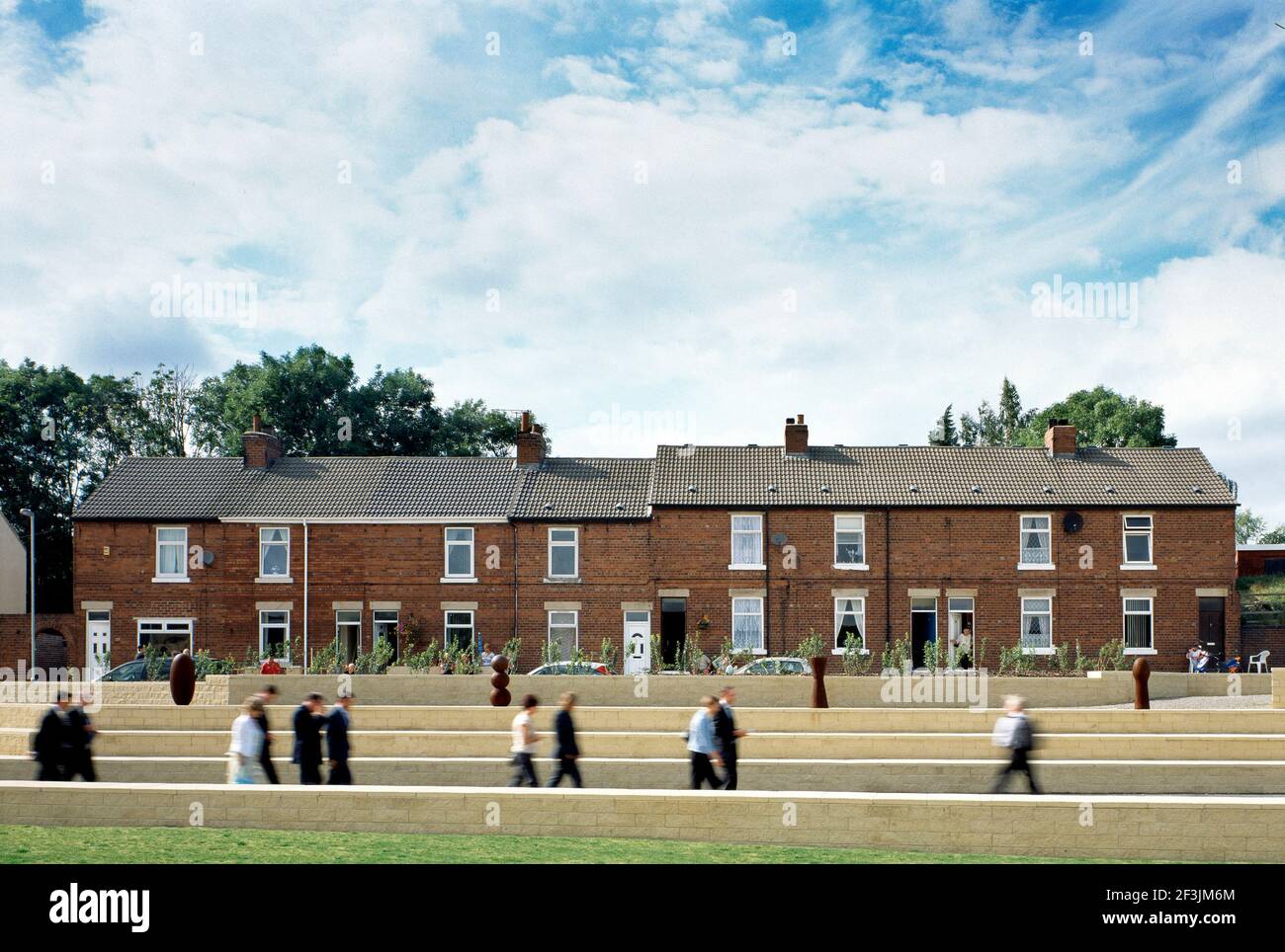 Persone che camminano di fronte a case a schiera, Fryston, West Yorkshire. Foto Stock