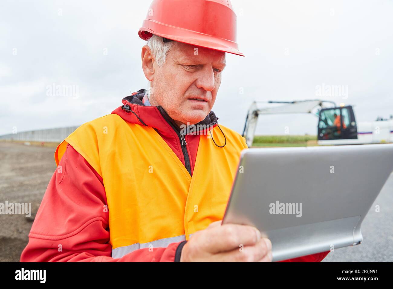I lavoratori edili come responsabili del sito durante la pianificazione delle costruzioni nel nuova area di sviluppo con il tablet Foto Stock