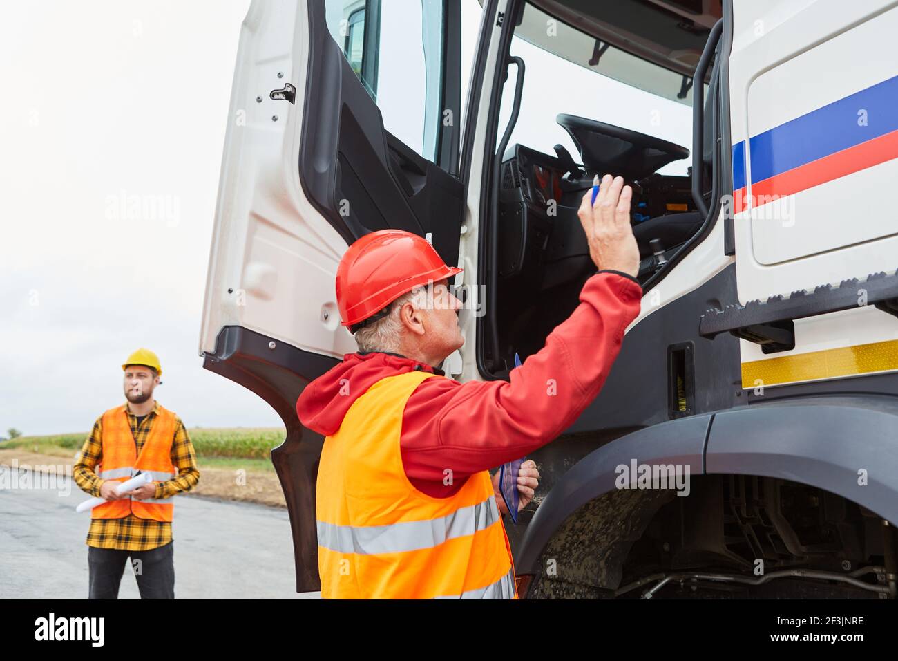 Il lavoratore addetto alla costruzione fornisce ai conducenti di autocarri un'istruzione sulla costruzione sito di costruzione stradale Foto Stock