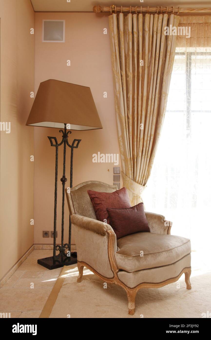 Poltrona e lampada standard in angolo della camera da letto principale con luminoso sunlight attraverso le finestre adiacenti | | Designer: Michael Nicholas Foto Stock