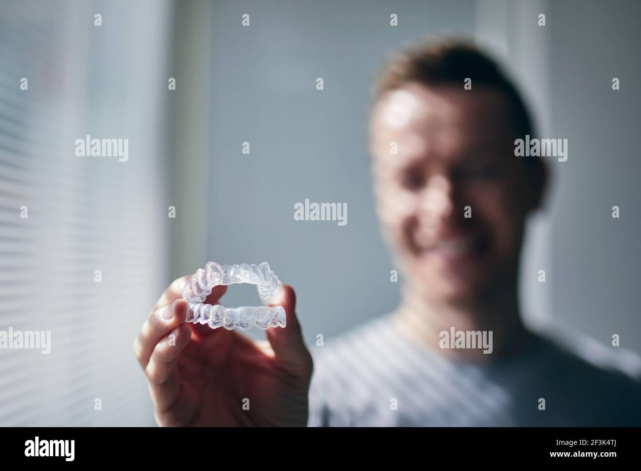 Sorridente giovane che tiene i vassoi per i denti sbiancanti. Temi salute dentale, cura e bellezza. Foto Stock