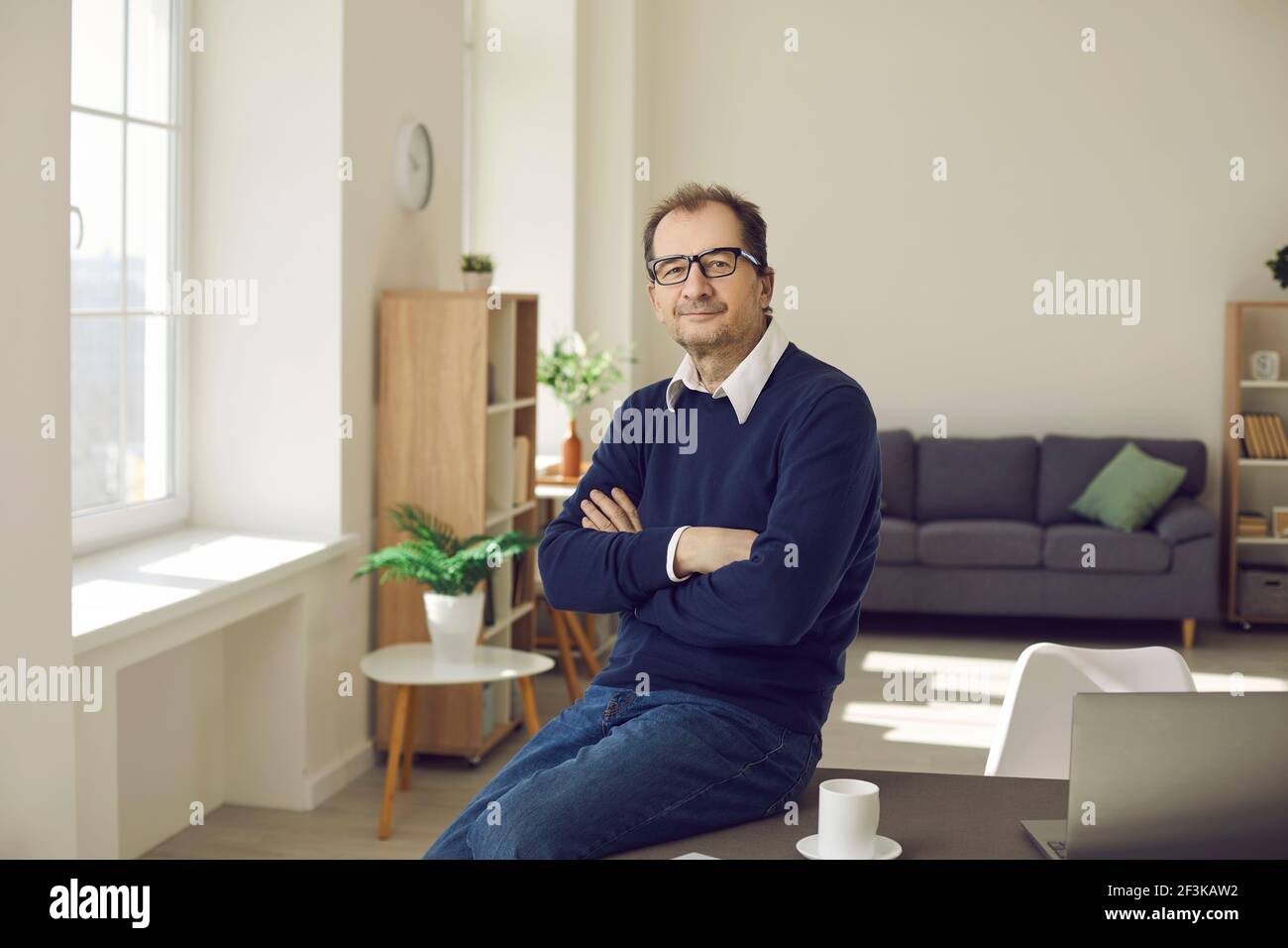 Ritratto di un uomo d'affari sorridente e rilassato di mezza età in abiti e bicchieri casual. Foto Stock