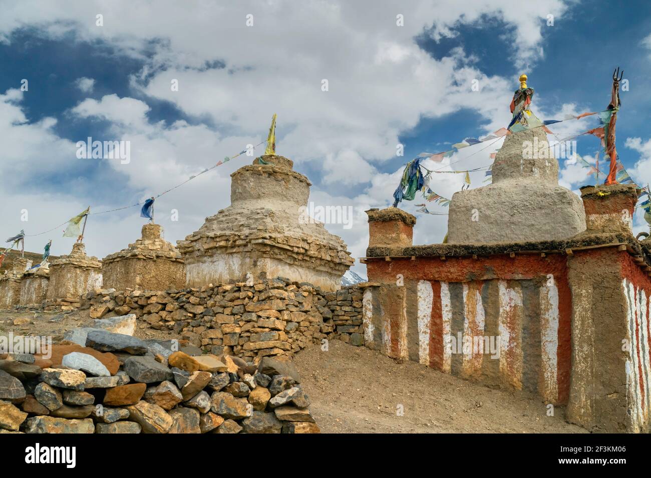 Antichi monumenti buddisti, Chortens e Stupa, con pareti in pietra a secco sotto il cielo blu nuvoloso nel villaggio himalayano di Tashigang, Himachal Pradeesh, India. Foto Stock