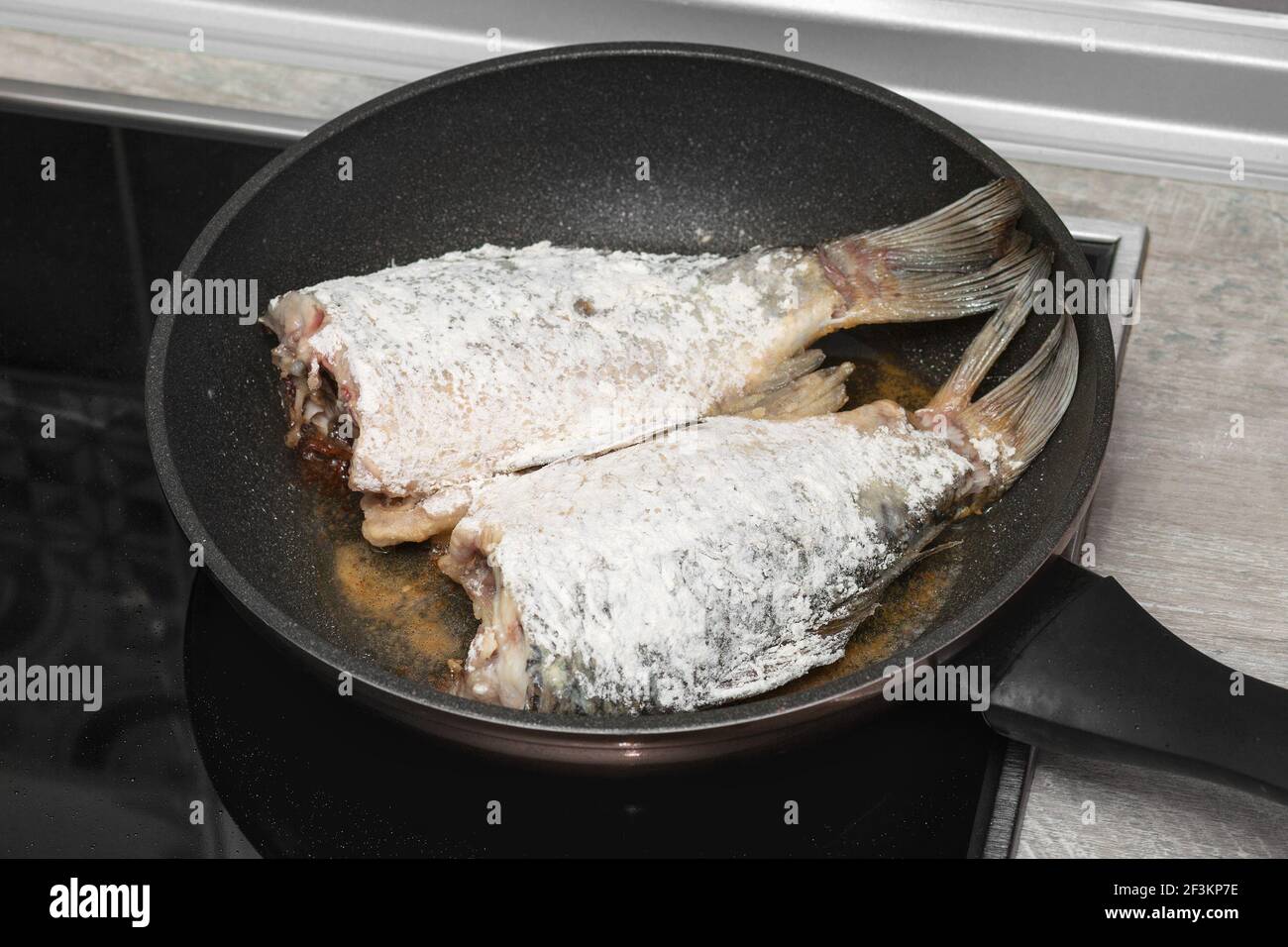 Primo piano di carpa crogiana di pesce fritta in una padella in una cucina casalinga. Pesce, sbucciato per friggere. Foto Stock