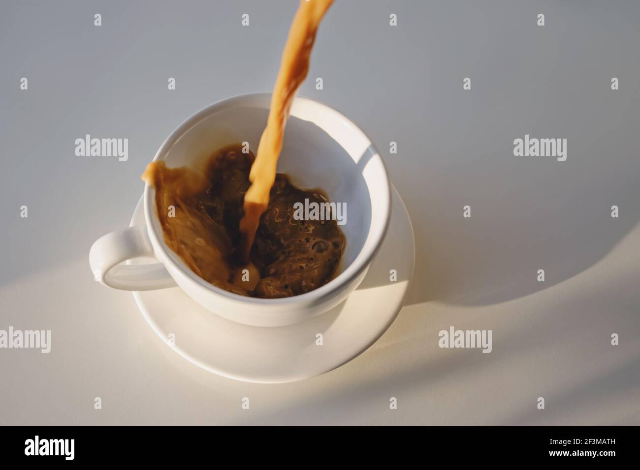 Versare il caffè in una tazza creando schizzi Foto Stock