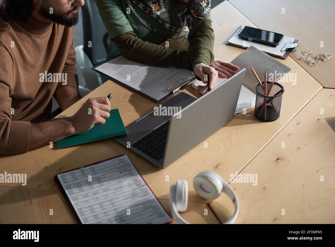 Primo piano delle persone che lavorano con il computer portatile per lavorare su presentazione online in team in ufficio Foto Stock