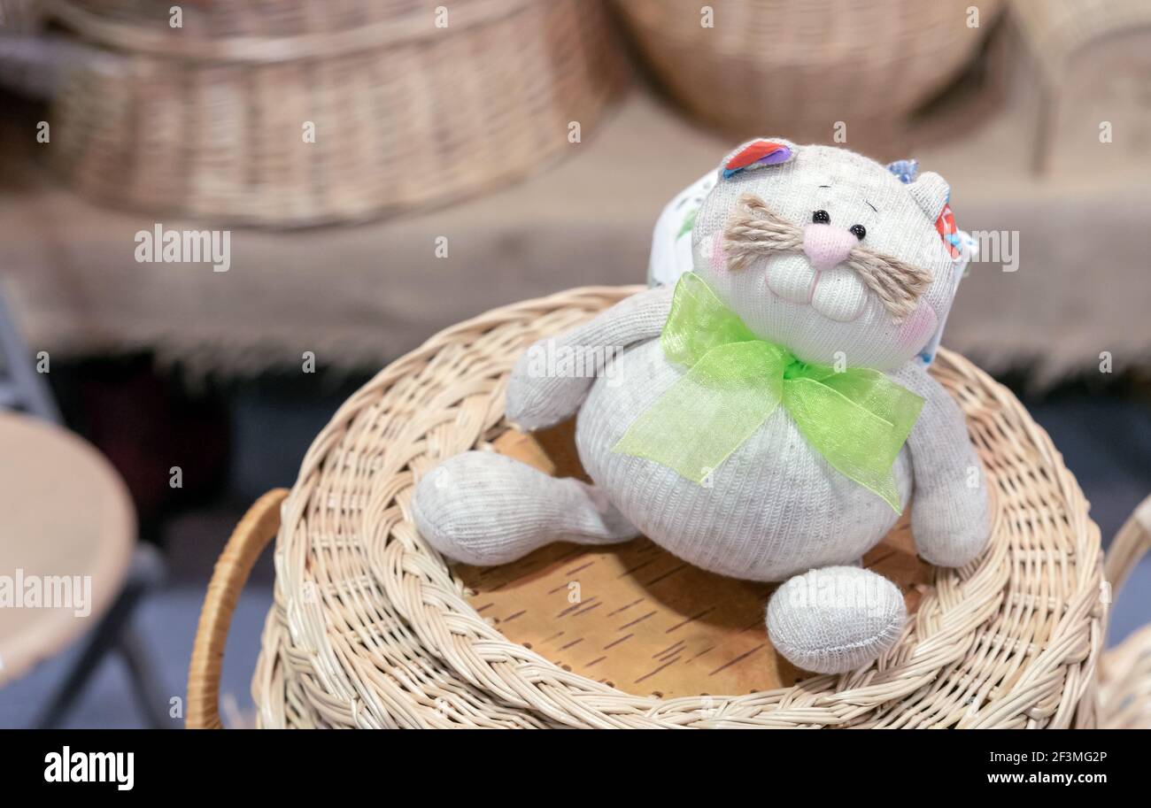 Gattino in tessuto con un arco verde su un cestino di vimini. Foto Stock