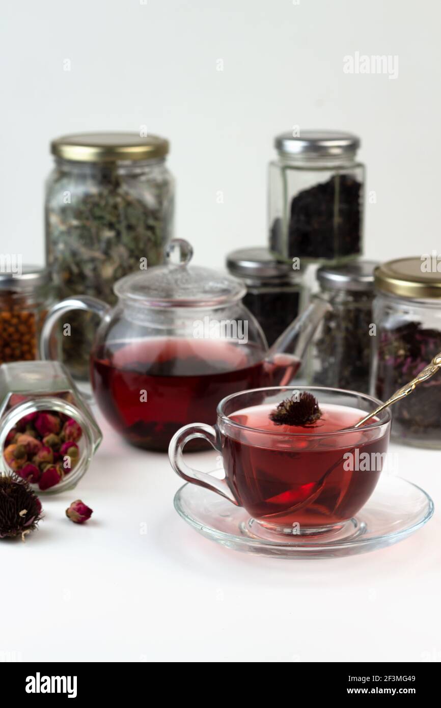 Tè alle erbe fatto in casa. Un rimedio che aumenta l'immunità e allevia lo stress. Teiera in vetro e tè con una bevanda sana. Vasi trasparenti con erbe secche Foto Stock