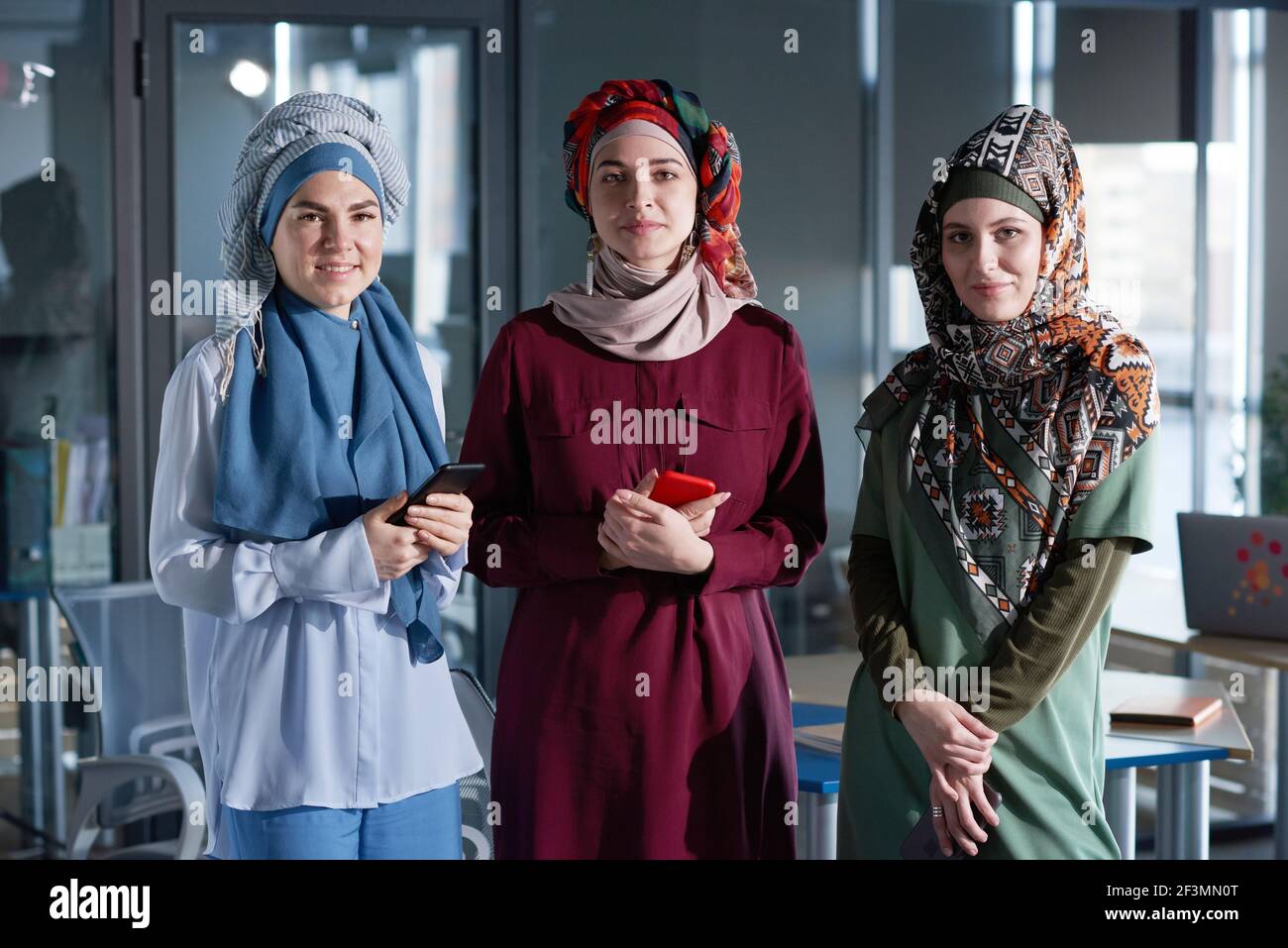 Ritratto di tre donne in hijabs guardando la macchina fotografica mentre stare insieme in ufficio Foto Stock