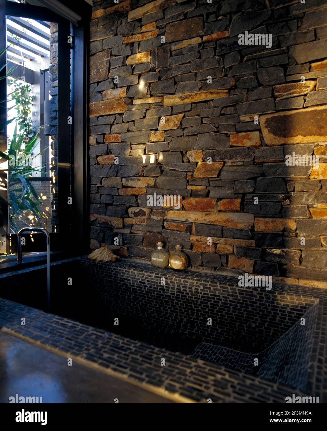 Vasca da bagno incassata con parete in pietra a vista, Bali Foto Stock