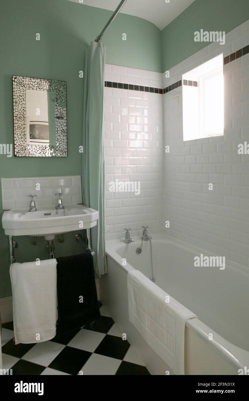 Un bagno tradizionale con pareti verdi e piastrelle in ceramica bianca. Foto Stock