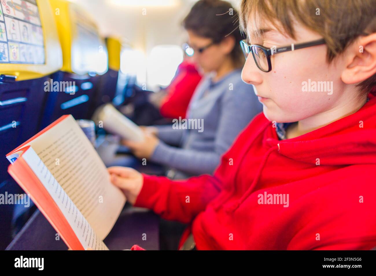 Passeggeri su un volo aereo che legge Foto Stock