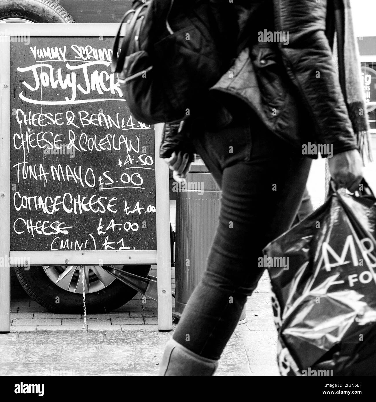 Londra UK, marzo 17 2021, donna anonima che cammina oltre una stall mobile del mercato alimentare pop-up che trasporta UNA borsa della spesa di plastica Foto Stock