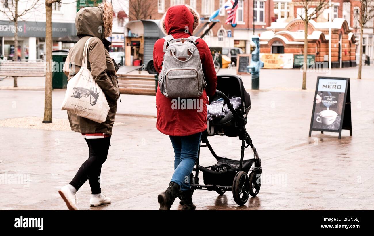 Londra UK, marzo 17 2021, Two Woman with A Baby Stroller Passeggiate lungo una High Street nella pioggia Foto Stock