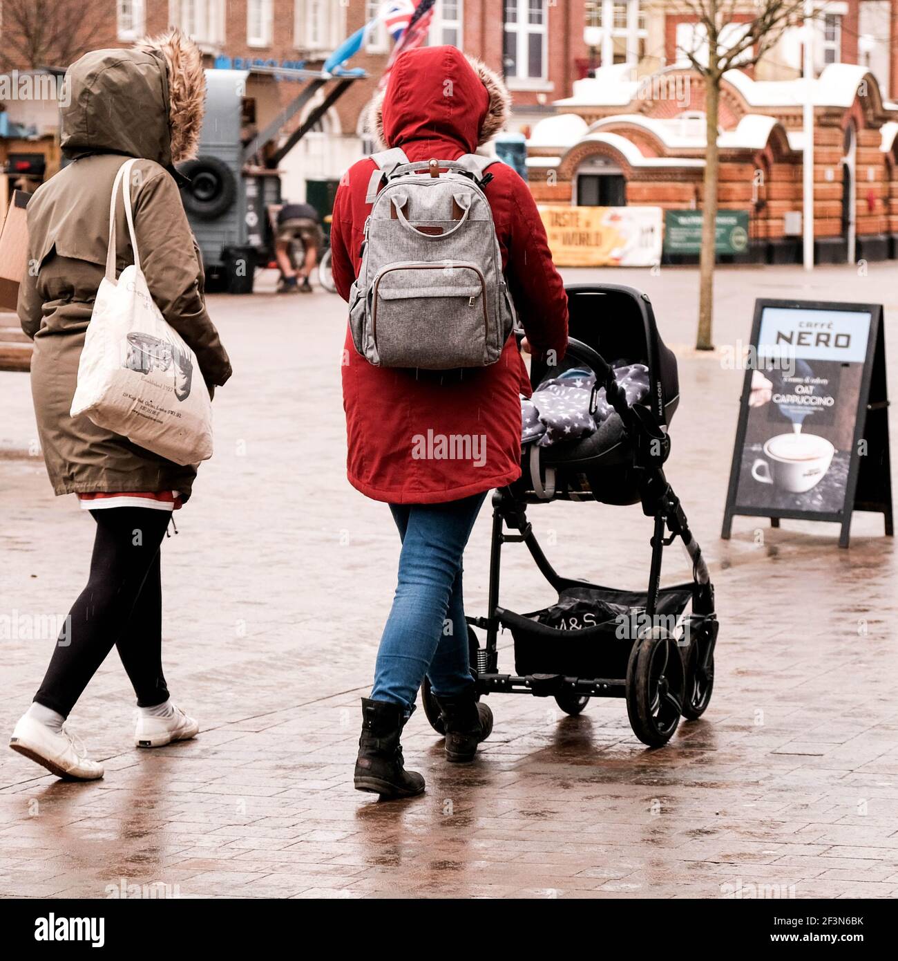 Londra UK, marzo 17 2021, Two Woman with A Baby Stroller Passeggiate lungo una High Street nella pioggia Foto Stock