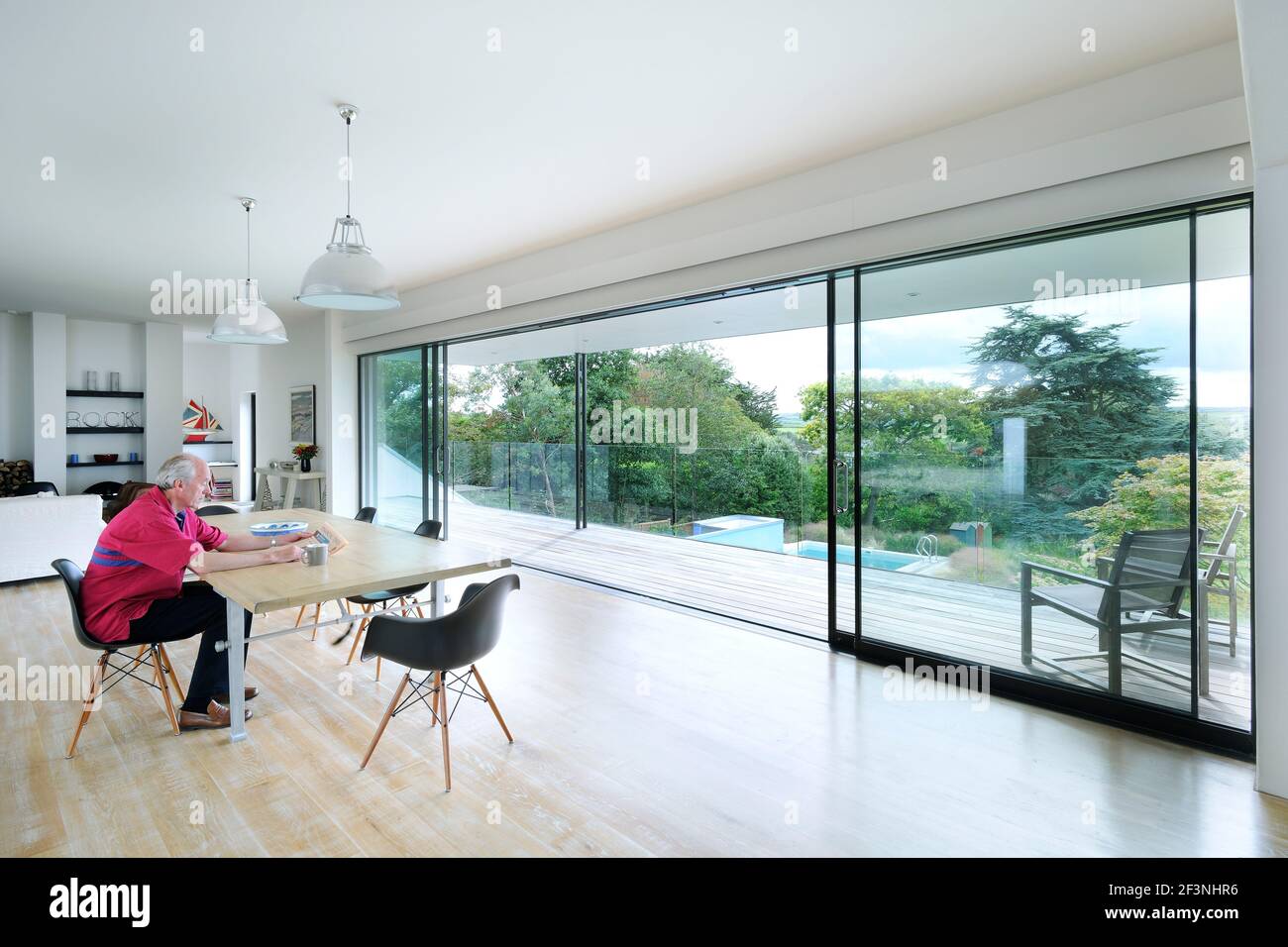 Il principale spazio abitativo, Richard Peirson seduto al tavolo da pranzo. Vista sulla parete vetrata e sul balcone - Stan Bolt Architect (www.stantecturearchect Foto Stock