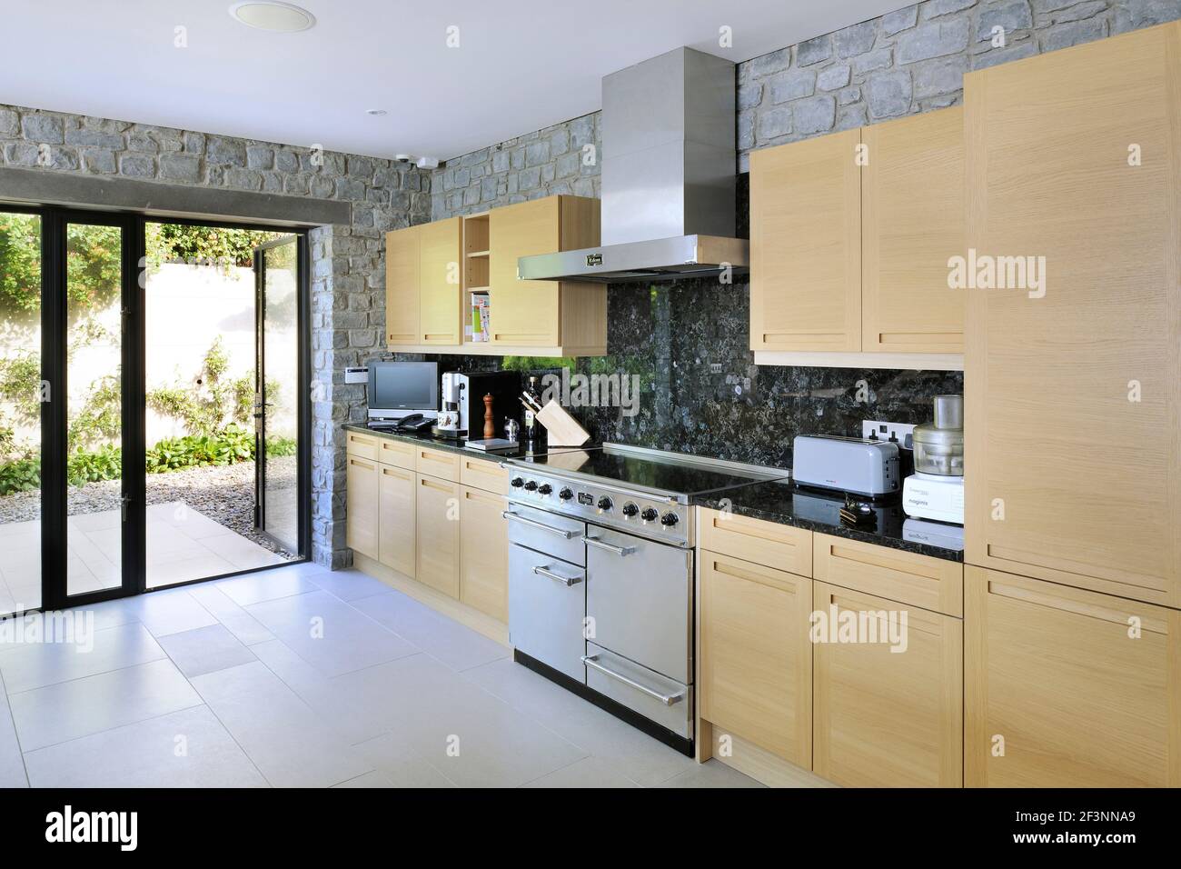 Gli spazi interni di una casa moderna sulle scogliere che si affacciano sul mare. Grandi pannelli e pareti in vetro, ripiani e divisori in legno. Cucina a Foto Stock