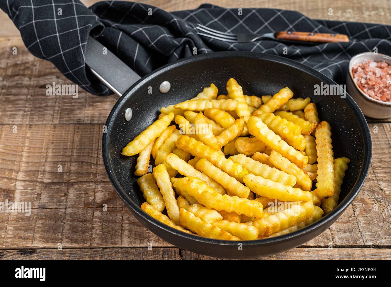 Fritto forno a grinze patate fritte bastoni in una padella. Sfondo di  legno. Vista dall'alto Foto stock - Alamy