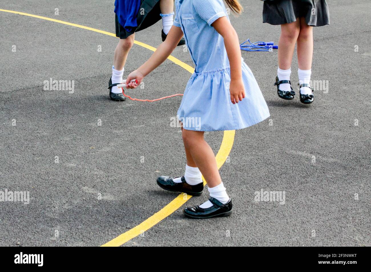 Scolari primari che giocano in un parco giochi scolastico in una pausa tra le lezioni in classe. Foto Stock