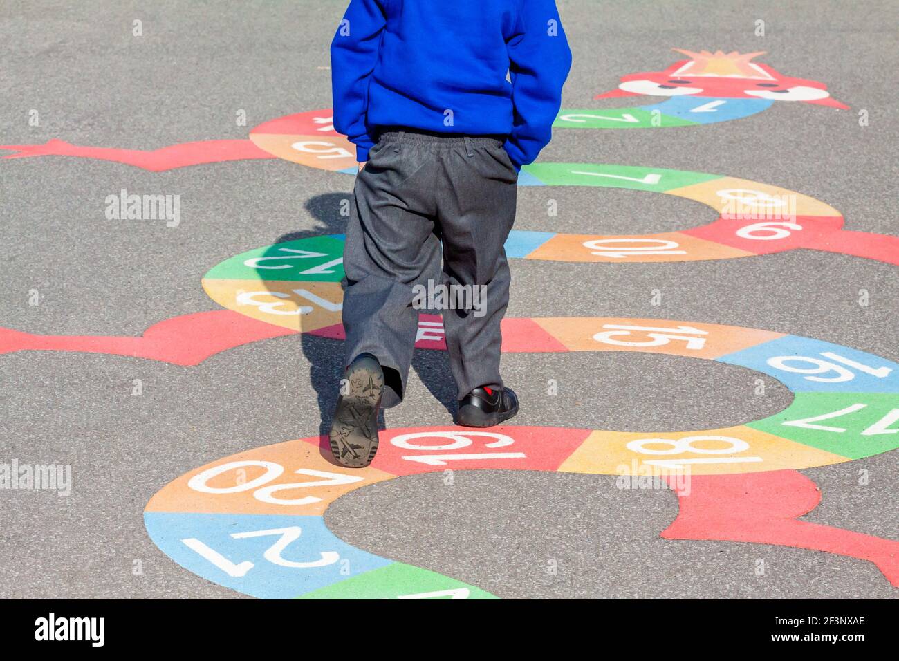 Bambino della scuola elementare che gioca in un parco giochi della scuola in una pausa tra le lezioni in classe. Foto Stock