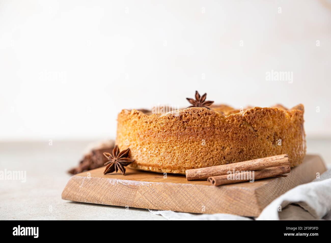 Torta di mele con cannella su tavola di legno, fondo di cemento chiaro. Torta di semola con mela e spezie. Mannik fatto in casa. Messa a fuoco selettiva. Foto Stock