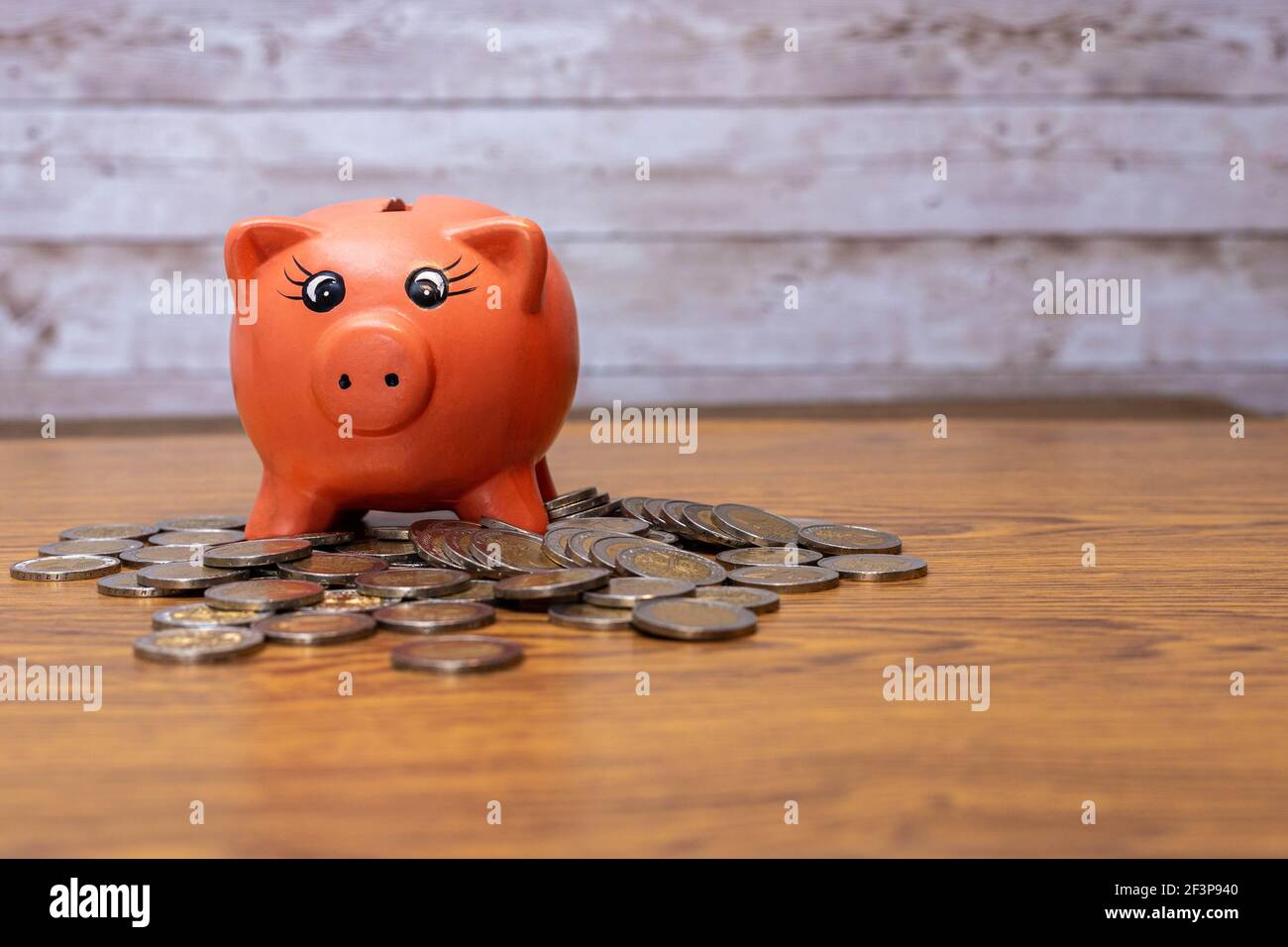 fuoco selettivo di un maiale di ceramica rosa per salvare piazzato su monete sul tavolo con spazio di copia in concetto di economia finanziaria Foto Stock