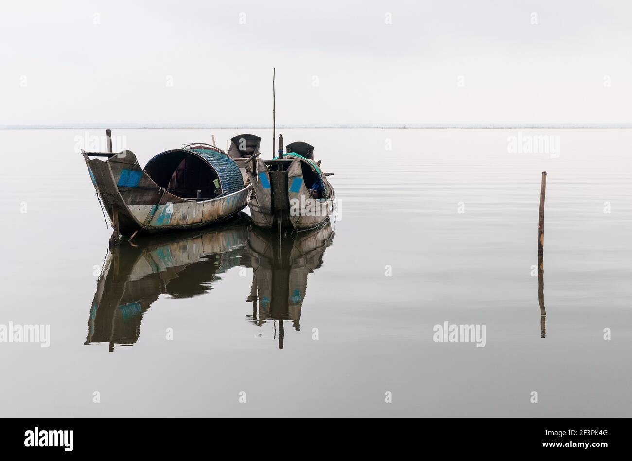 Due barche da pesca di gamberi sampan con un riflesso in un lago tra Hue e Hoi An, Vietnam centrale. Foto Stock