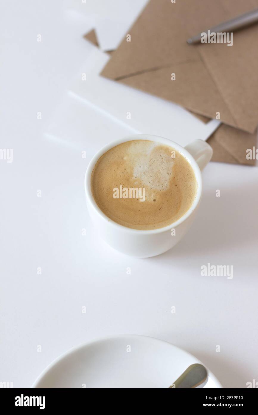 Piano di studio dal design minimale. Caffè fresco e Stationery su sfondo bianco. Foto Stock