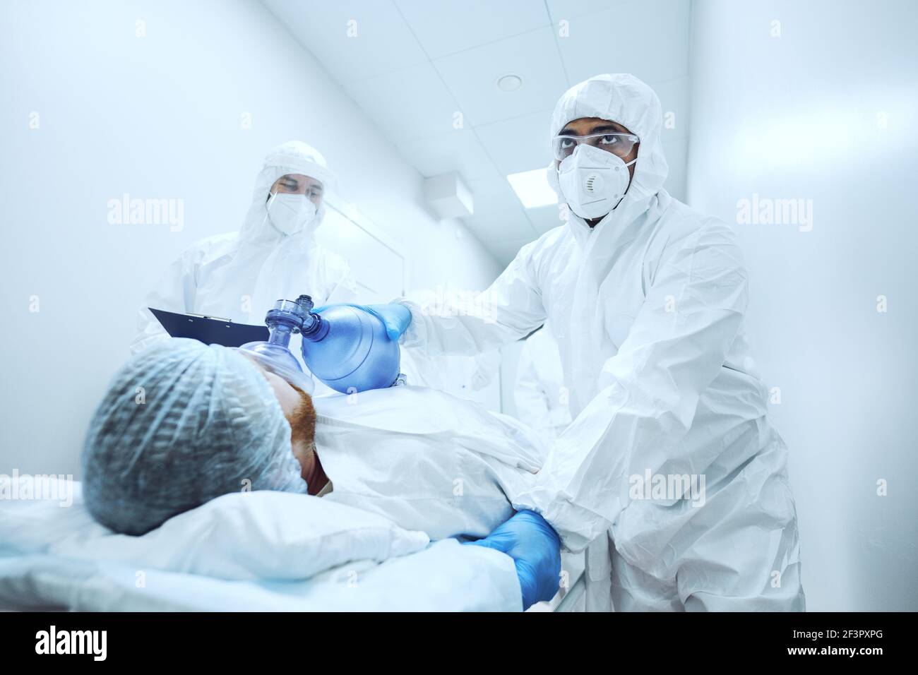 Chirurghi in uniforme protettiva che fa il massaggio cardiaco per il paziente dentro sala operatoria Foto Stock