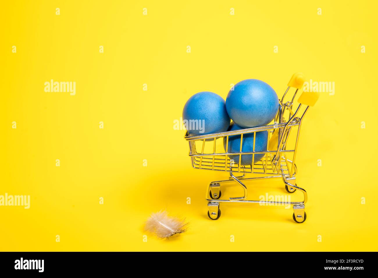 Carrello per lo shopping con uova di pasqua blu e piume. Spazio di copia Foto Stock