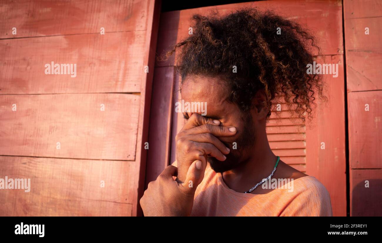 Triste uomo nero. Lunghi capelli ricci su un giovane di etnia brasiliana. Concetto di tristezza pandemica e ansia. Uomo bearded Foto Stock