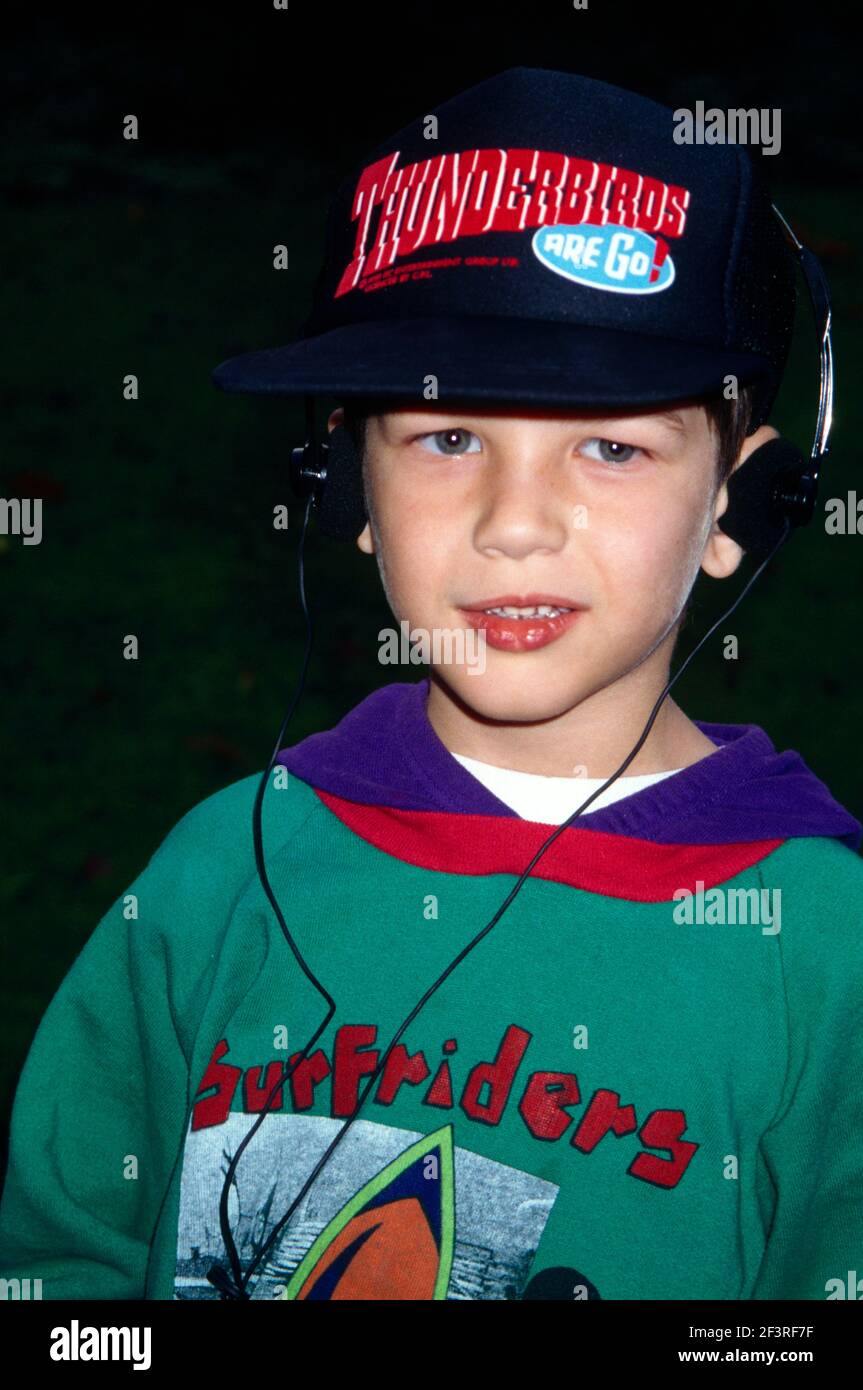 Ritratto di giovane ragazzo che indossa le cuffie sopra il cappello da baseball Thunderbirds Ascoltare Musica Surrey Inghilterra Foto Stock