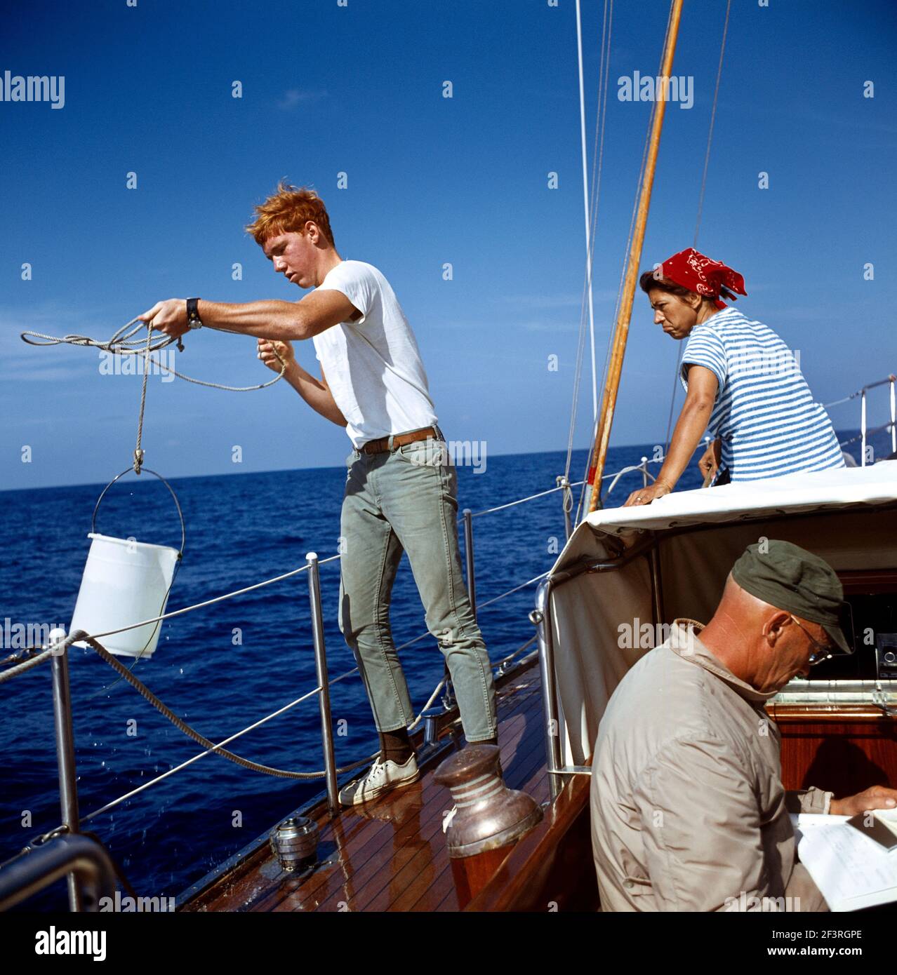 Uomo che riempie secchio con acqua di mare a bordo Barca a vela Foto Stock