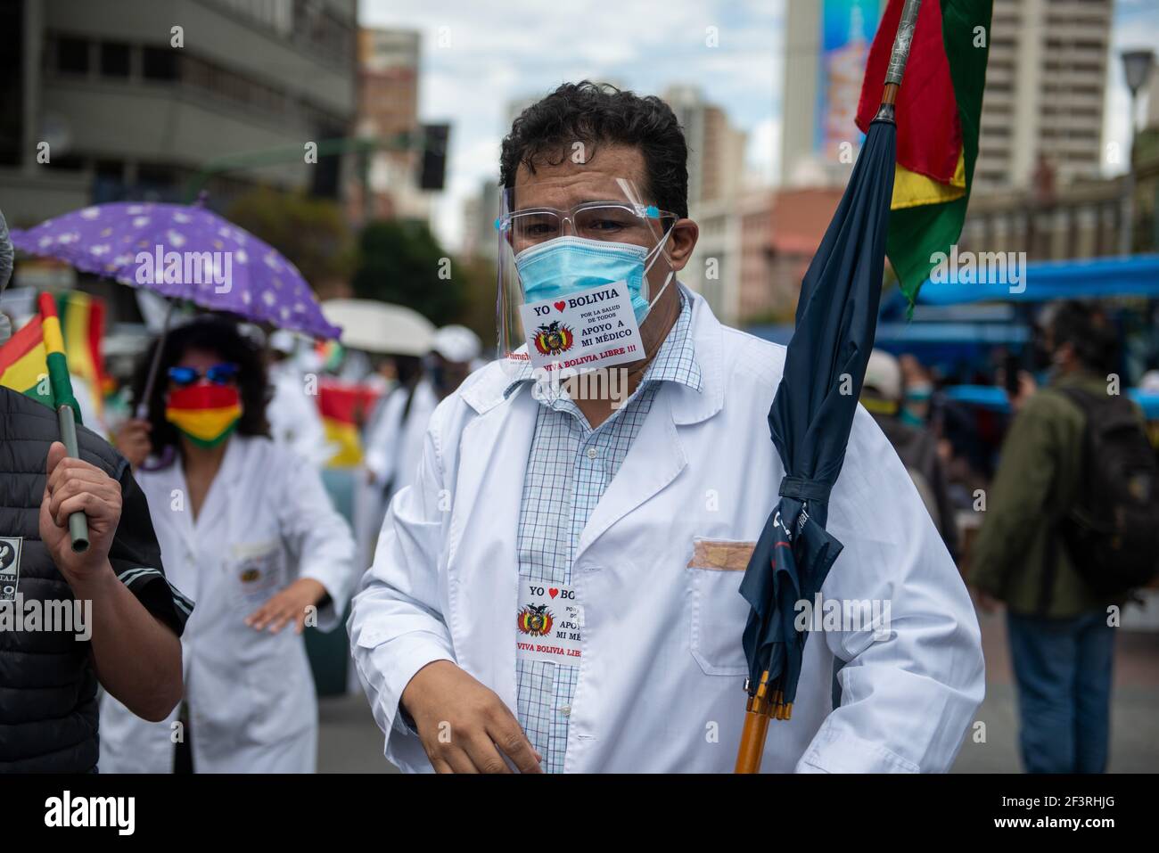 La Paz, Bolivia. 17 Marzo 2021. "Amo la Bolivia e sostengo il mio medico", è scritto sulla maschera di un dimostrante in un mantello bianco durante una protesta "per la democrazia". I manifestanti sono scesi di nuovo in piazza per l'arresto dell'ex presidente ad interim Anez e di altri ex ministri. Un gruppo di medici ha preso parte al raduno chiedendo l'abrogazione di una nuova legge che, a loro avviso, limita il loro diritto allo sciopero. Credit: Radoslaw Czajkowski/dpa/Alamy Live News Foto Stock