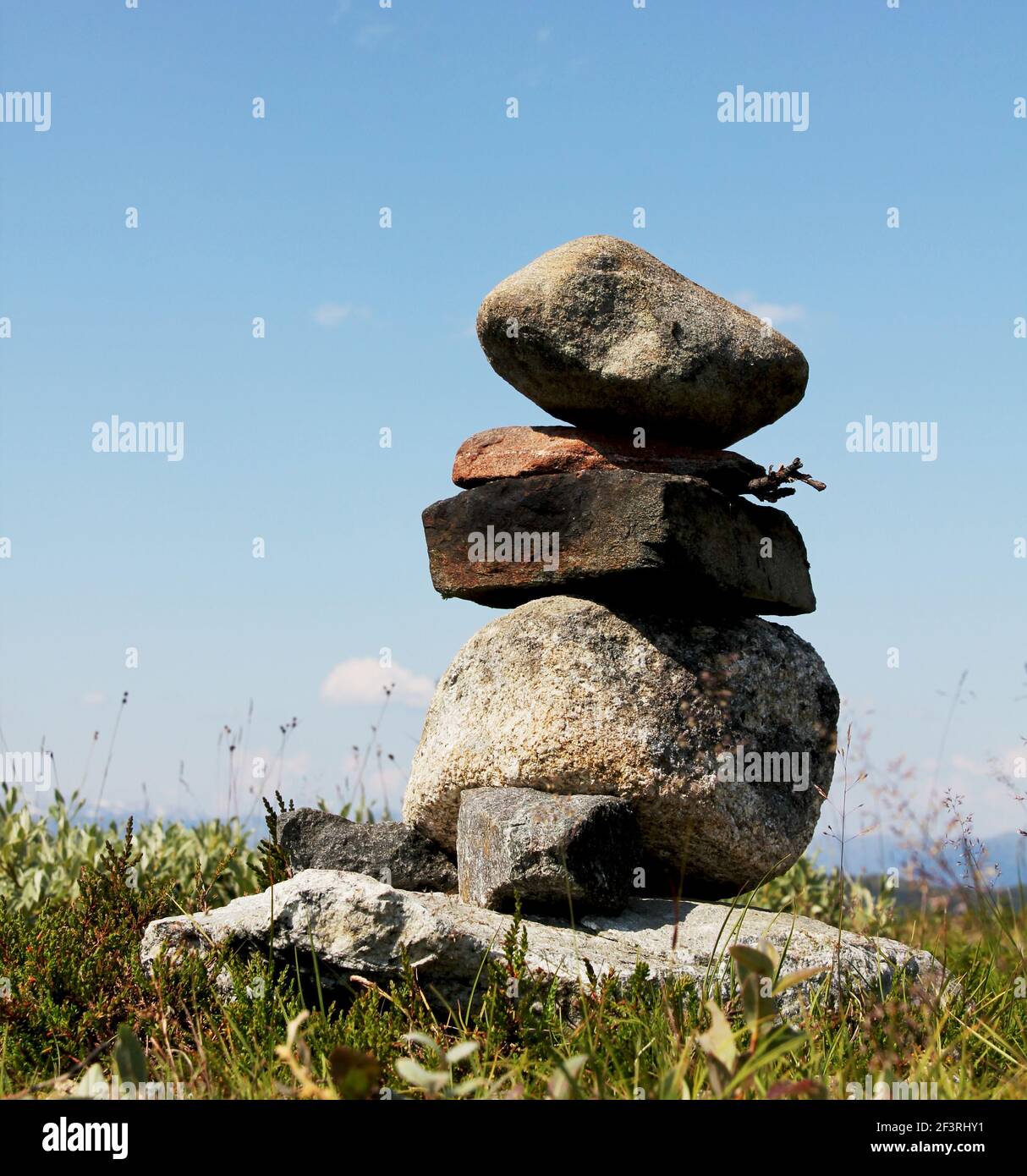 Una pila di pietre in equilibrio. Le pietre sono ruvide e la pila è in piedi in un campo di erba Foto Stock
