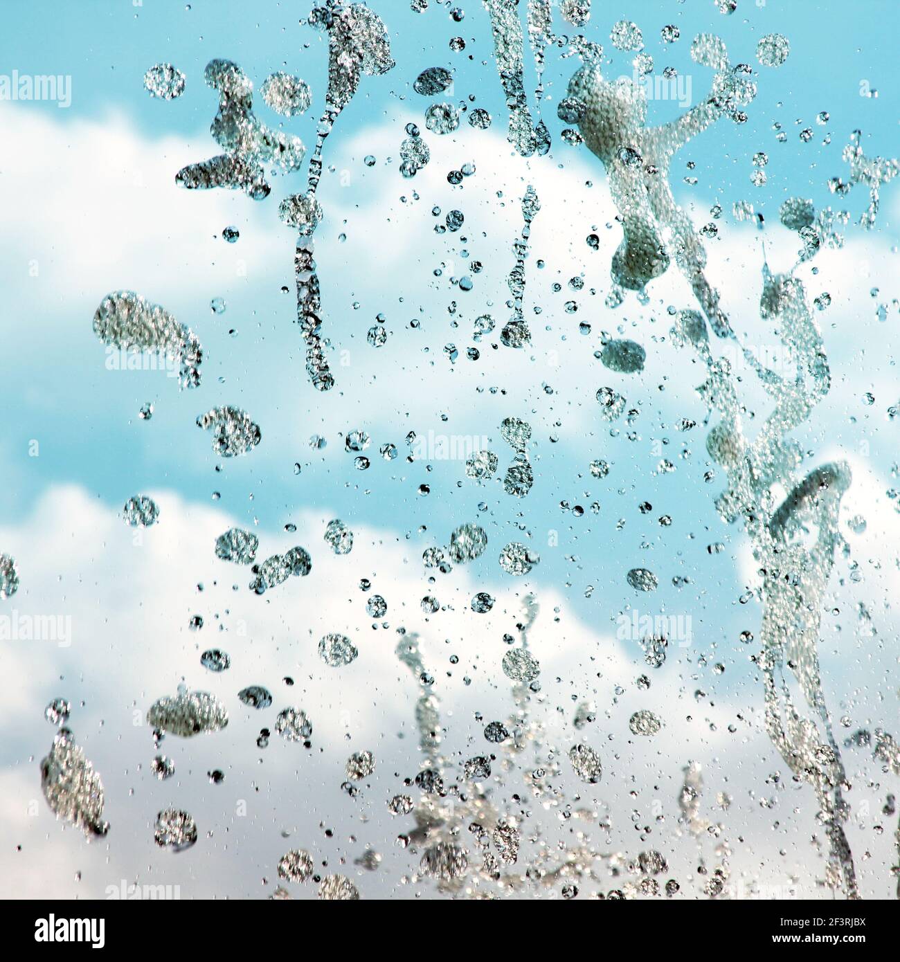 Un primo piano fa le gocce di una fontana d'acqua. Cielo blu con nuvole Foto Stock
