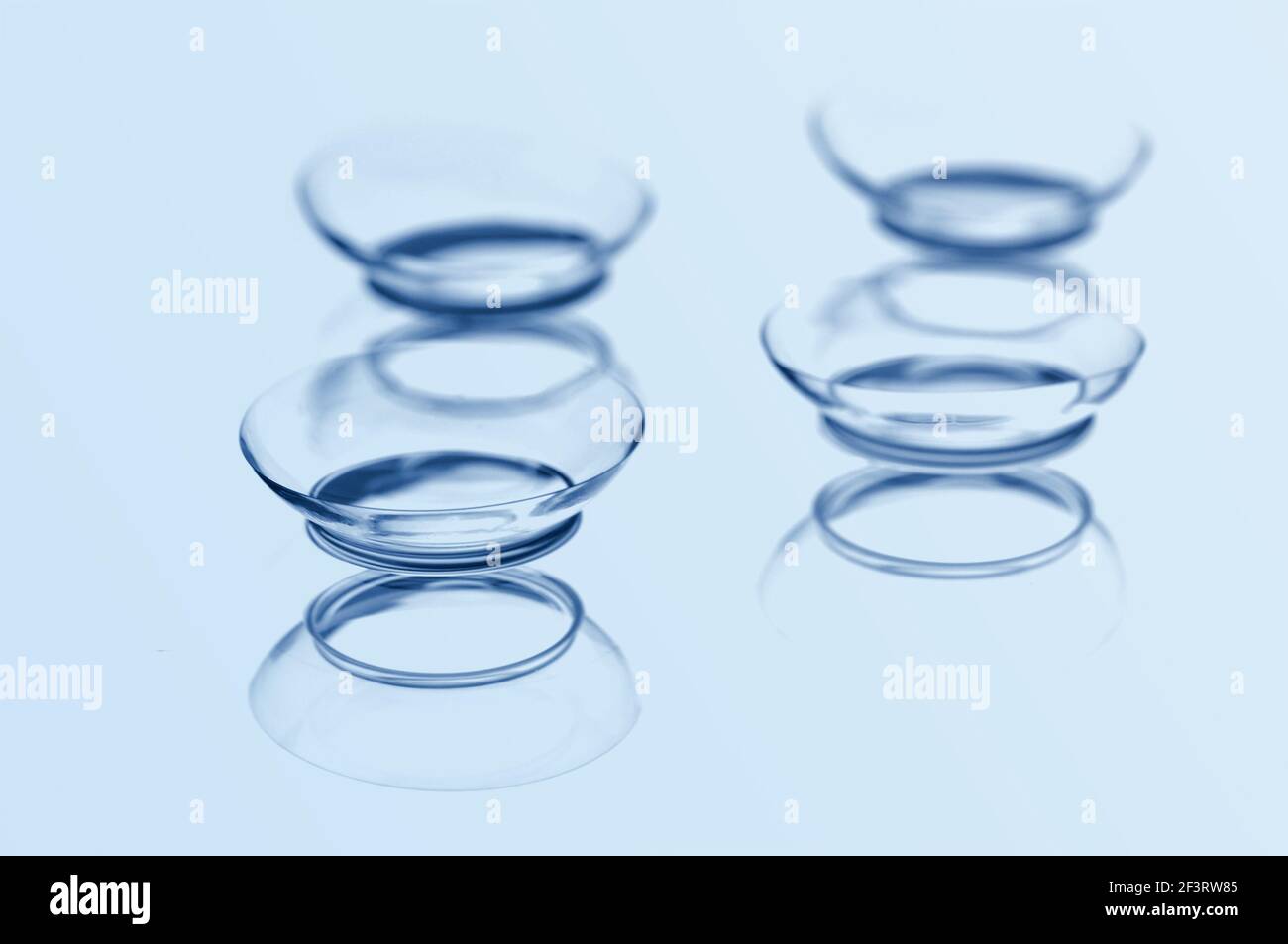 Quattro lenti a contatto con riflessione su sfondo blu. Mettere a fuoco l'obiettivo più vicino. Foto Stock