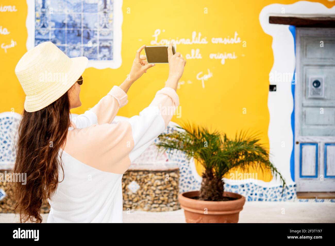 Giovane ragazza in vacanza in Sicilia scattando una foto con il suo telefono cellulare Foto Stock