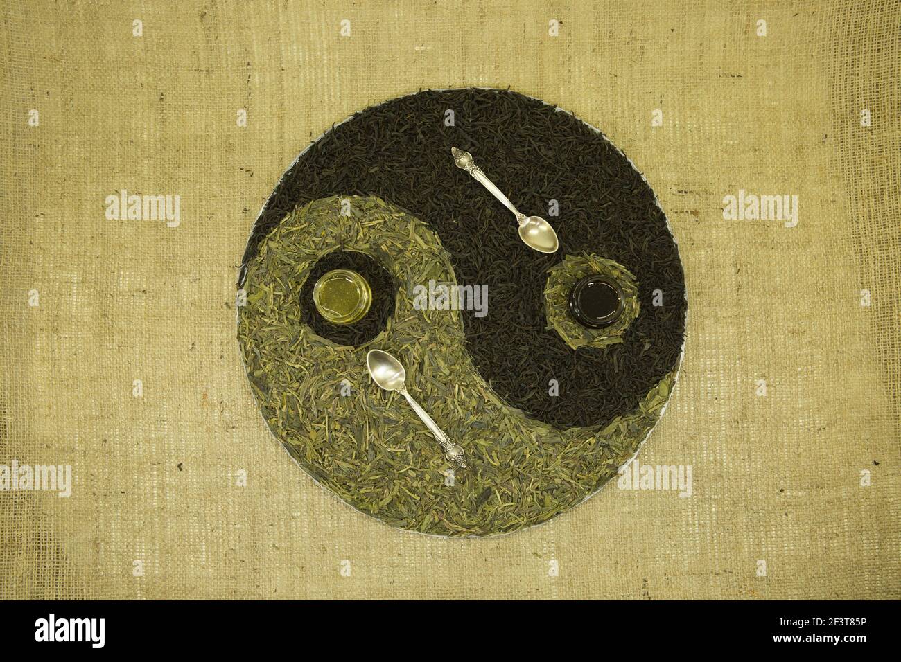 Il concetto di yin yang. Segno yin yang sullo sfondo del burlap. Sono stati utilizzati tè verde cinese Lundzyn, tè nero indiano e miele. Foto Stock