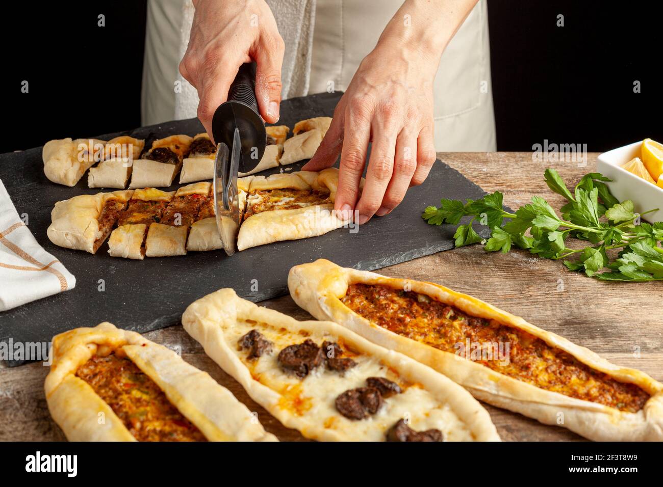 Il kasarli sucuklu pide e il kimali pide sono tradizionali piatti turchi simili alla pizza con condimenti di carne e formaggio. Vengono serviti con limone An Foto Stock