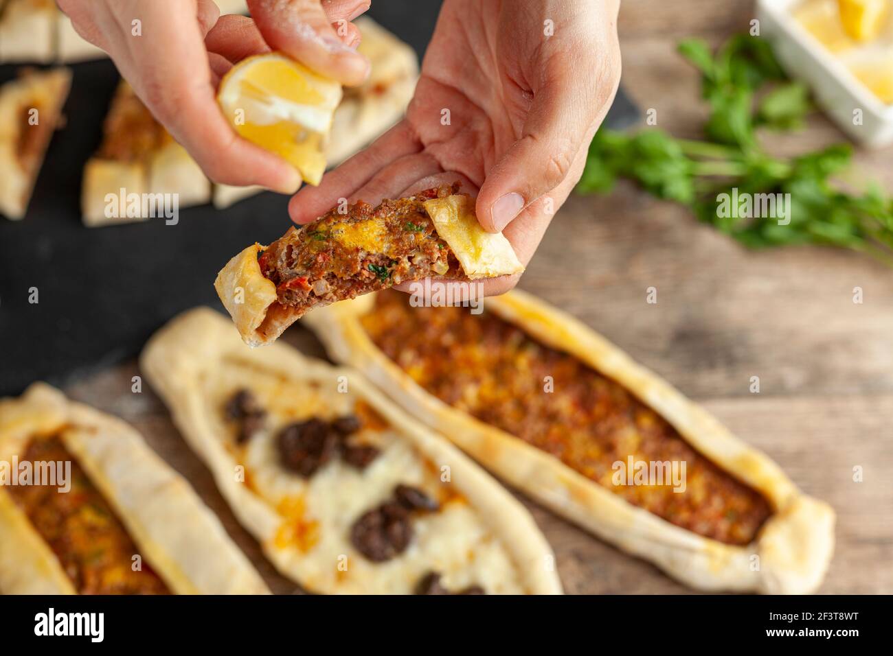 Il kasarli sucuklu pide e il kimali pide sono tradizionali piatti turchi simili alla pizza con condimenti di carne e formaggio. Vengono serviti con limone An Foto Stock