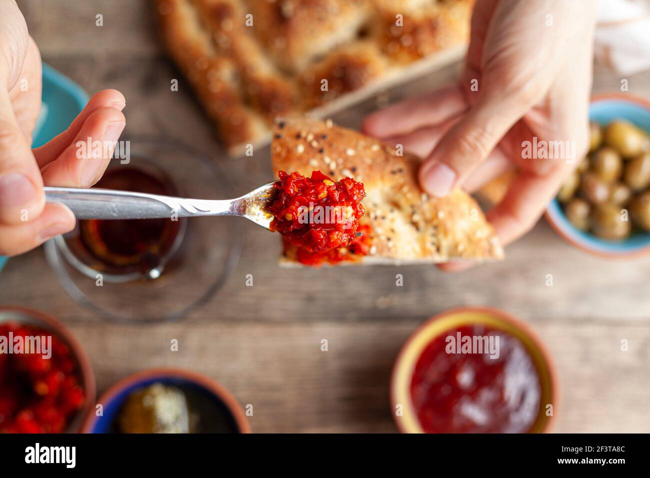 Sana colazione turca, con pomodoro a fette, cetriolo e formaggio feta bianco, piccole ciotole di marmellata di fragole, olive, miele, pasta di pepe. Donna è pu Foto Stock